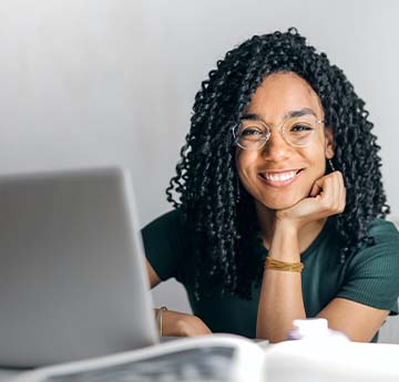 A student smiling whilst using a laptop