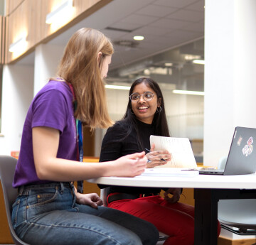 Two students chatting with their laptops open