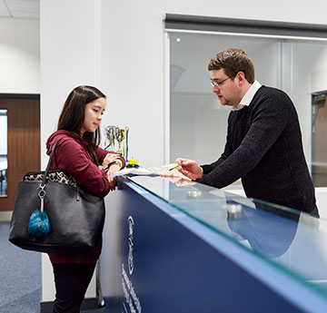 Reception helping a student with a query.