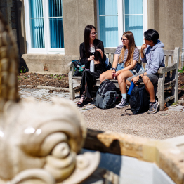 Students sitting on a bench socialising outside Singleton Abbey