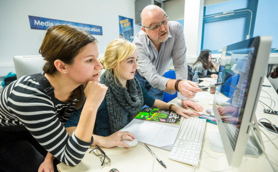 Students looking at PC in CAD lab being assisted by member of staff