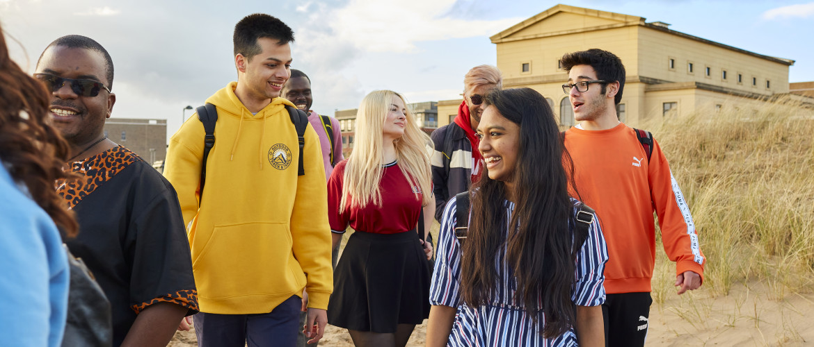 students walking on beach, building in background