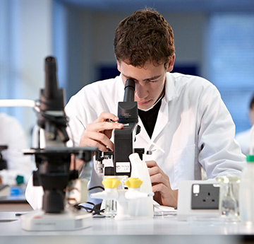 A male staff member looking into a microscope. 