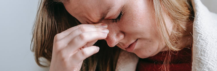 a woman rubbing her eyes in pain