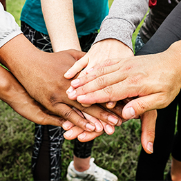 People standing in a circle touching hands