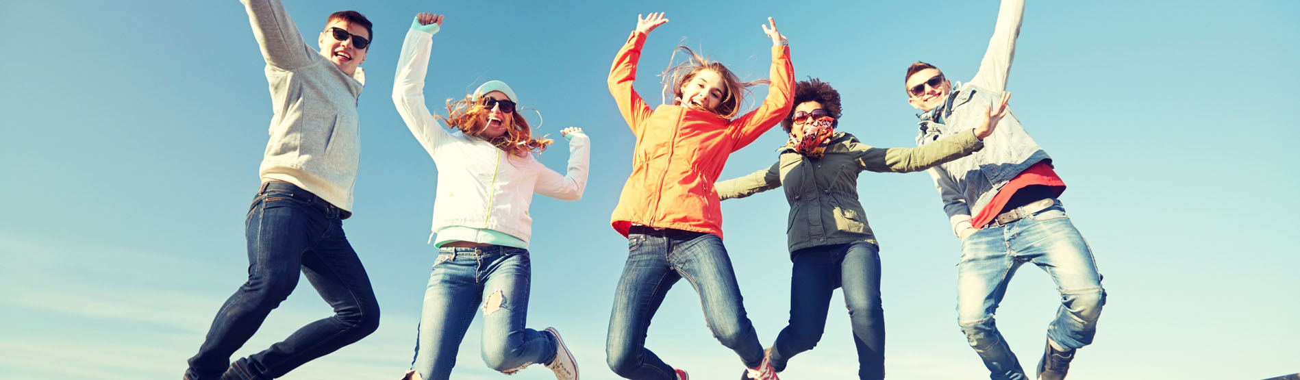 Students jumping in air against blue sky background